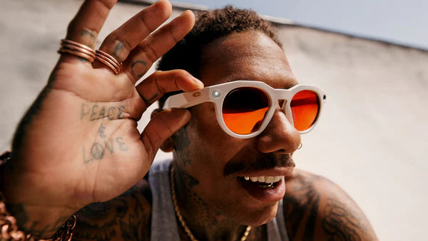 Man with tattooed hands wearing white sunglasses with orange lenses